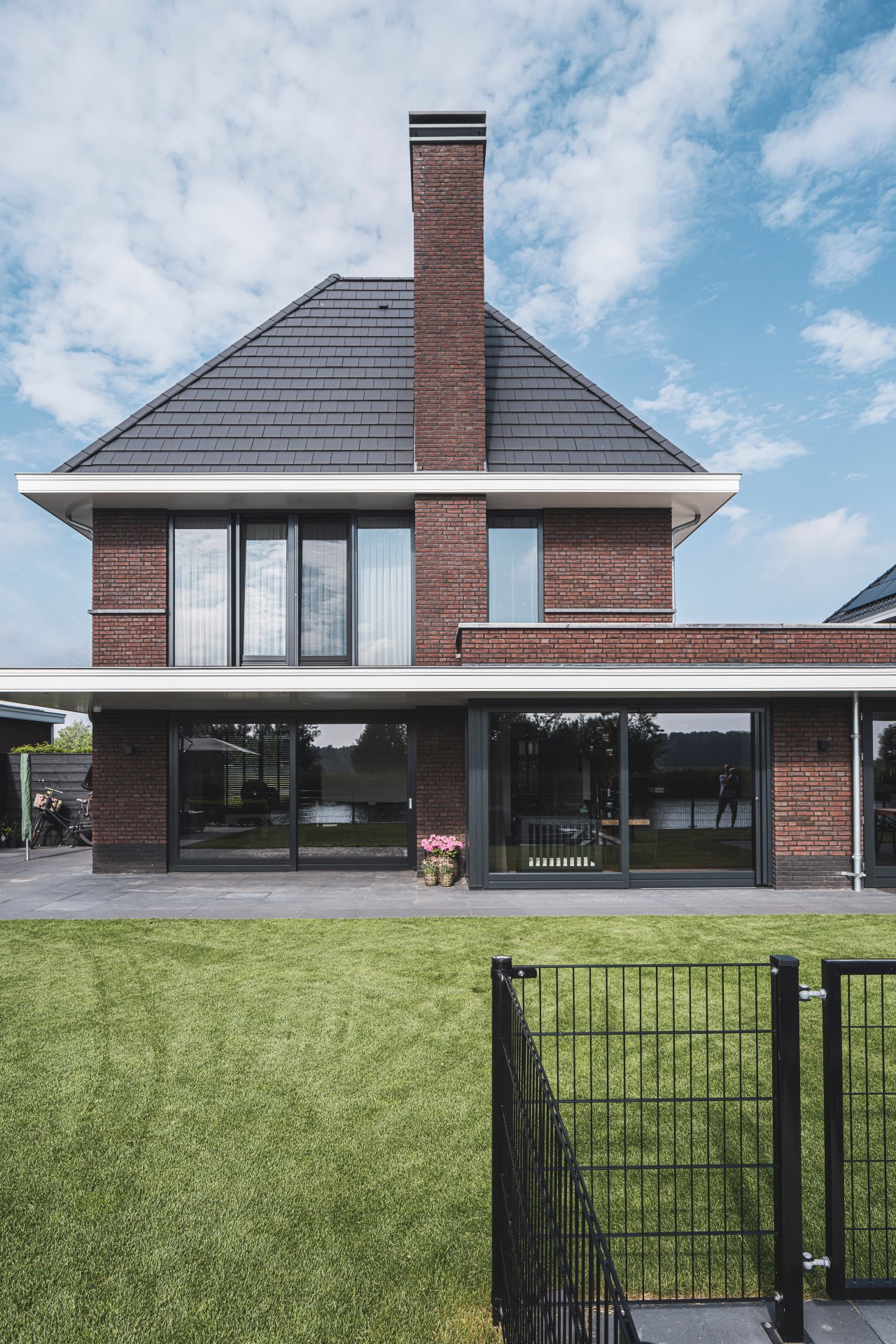 Moderne villa met rood metselwerk en zwarte kozijnen, ontworpen door architect Alblasserwaard &ndash; veel licht en zicht in architectuur.