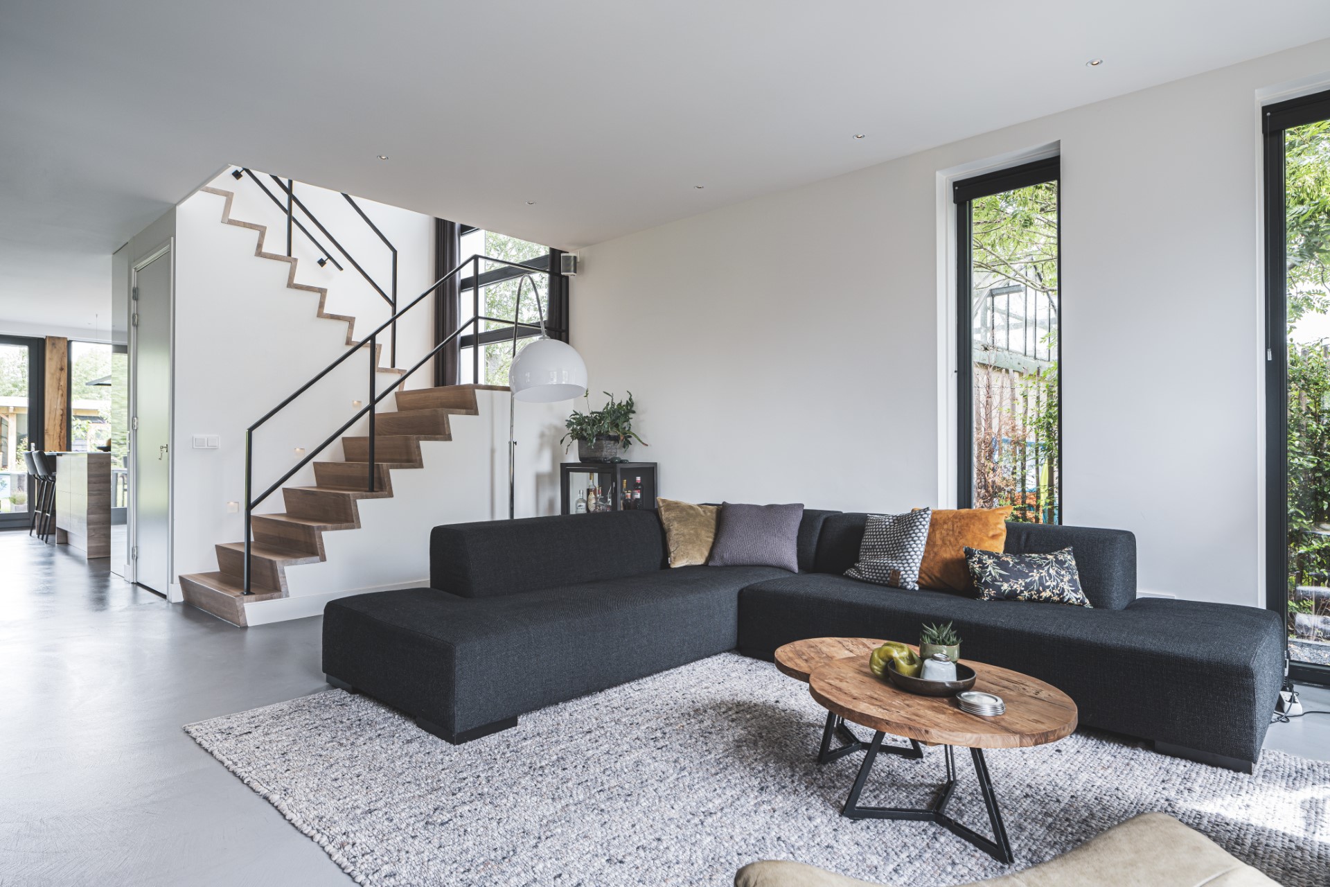 Lichte woonkamer met zwarte trap, grote raampartijen en open indeling &ndash; moderne woning ontworpen door Bongers Architecten