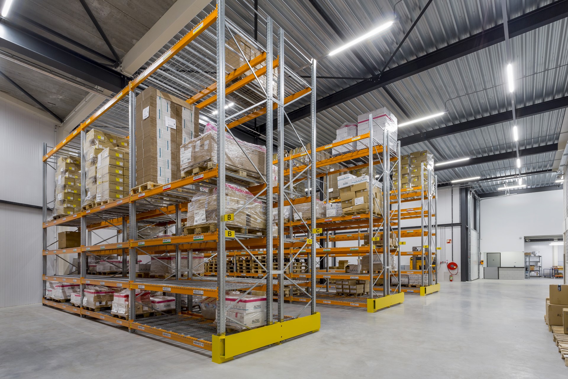 Bedrijfshal in modern bedrijfspand met stalen vakwerkspanten, hoge stellingen en optimale logistiek &ndash; functioneel bedrijfspand ontwerpen