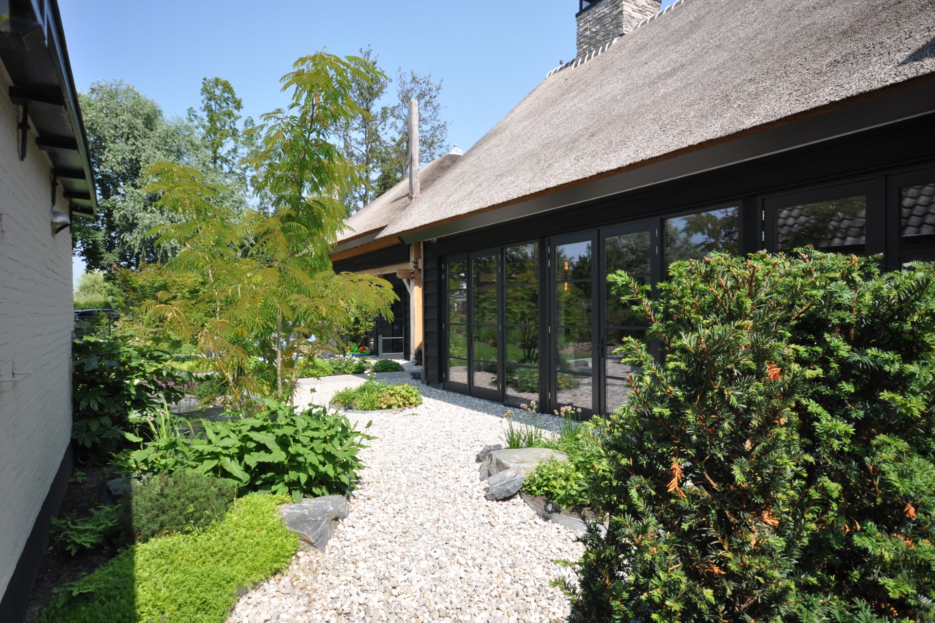 Verbouwing woonboerderij met rieten dak, moderne zwarte kozijnen en grindpad &ndash; architect Oud-Alblas voor duurzaam huis ontwerpen.