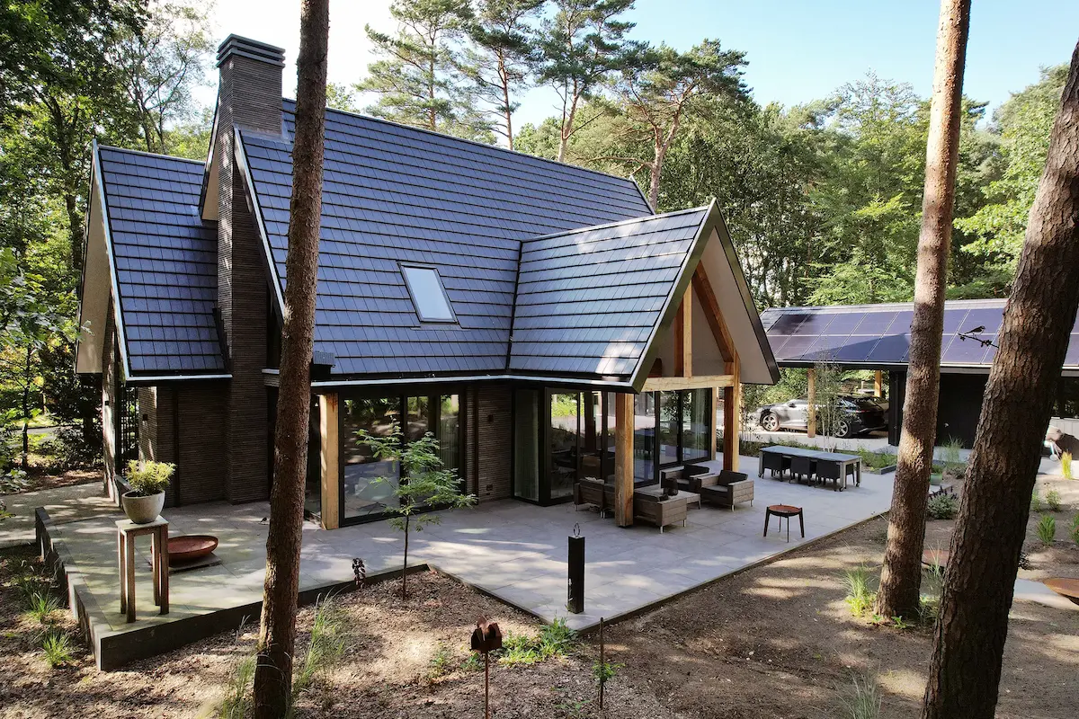 Moderne villa in bosrijke omgeving met donkere houten gevel en zadeldak &ndash; duurzaam ontworpen door Bongers Architecten.