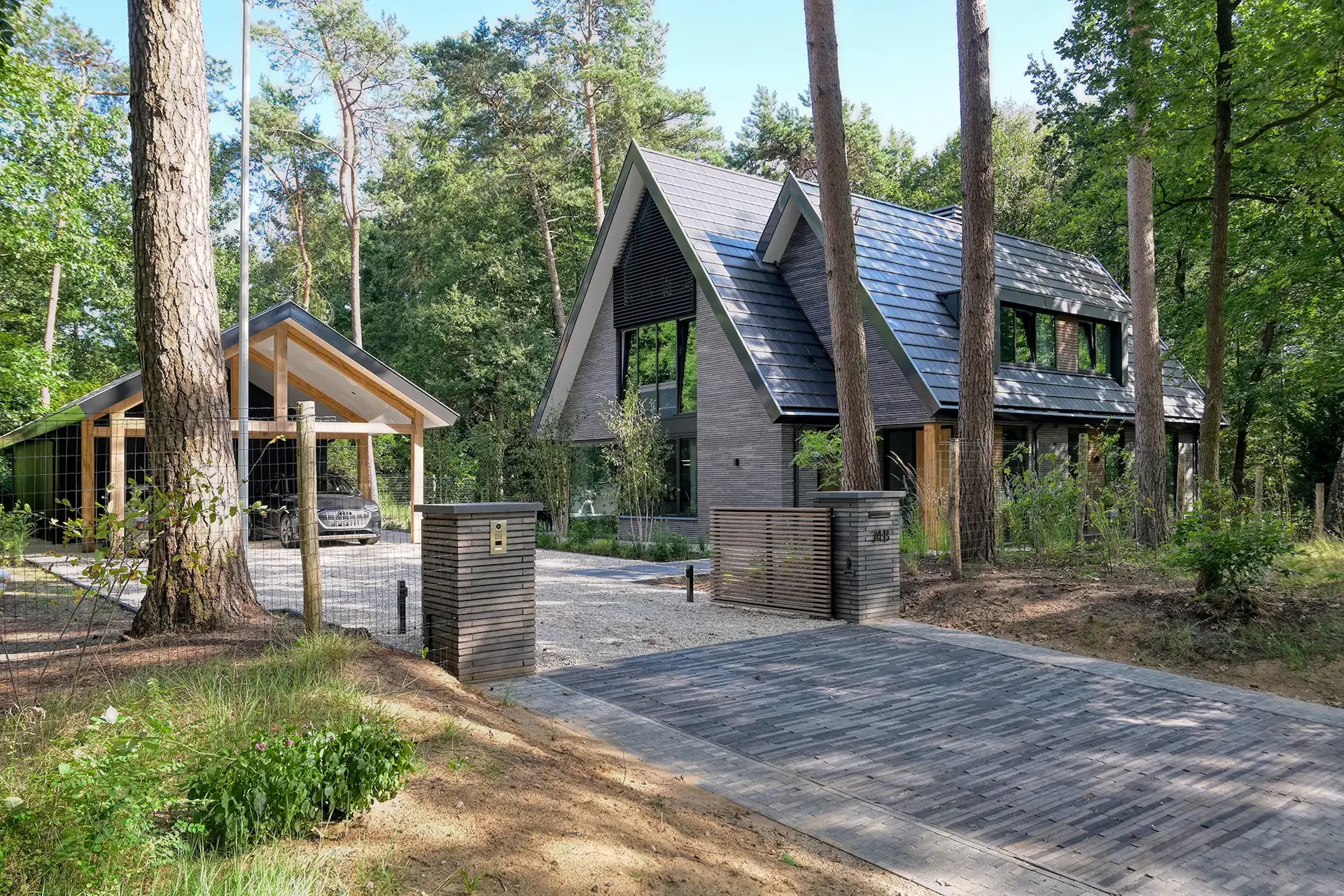 Moderne villa in bosrijke omgeving met donkere houten gevel en zadeldak &ndash; duurzaam ontworpen door Bongers Architecten.