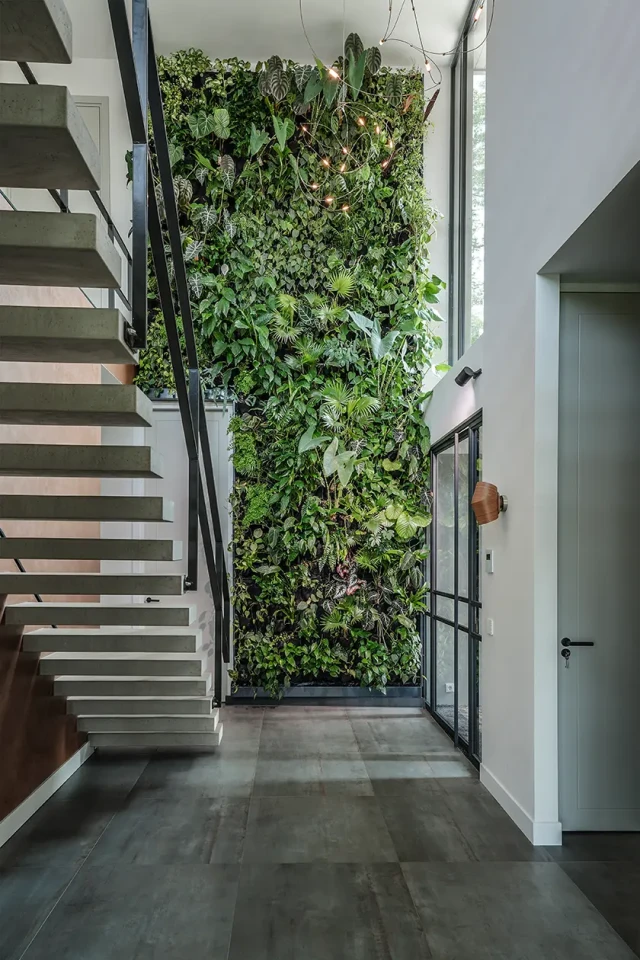 "Interieur met een adembenemende groene wand en een zwevende trap. Een perfecte balans tussen modern design en natuurlijke elementen