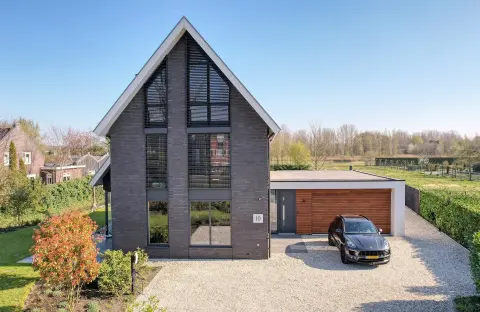 Moderne energiezuinige woning met een strak zadeldak, grote glaspartijen en houten accenten. Voorbeeld van een functioneel ontwerp door een architect in Oud-Alblas, met aandacht voor licht en zicht in architectuur en gericht op duurzaam huis ontwerpen doo
