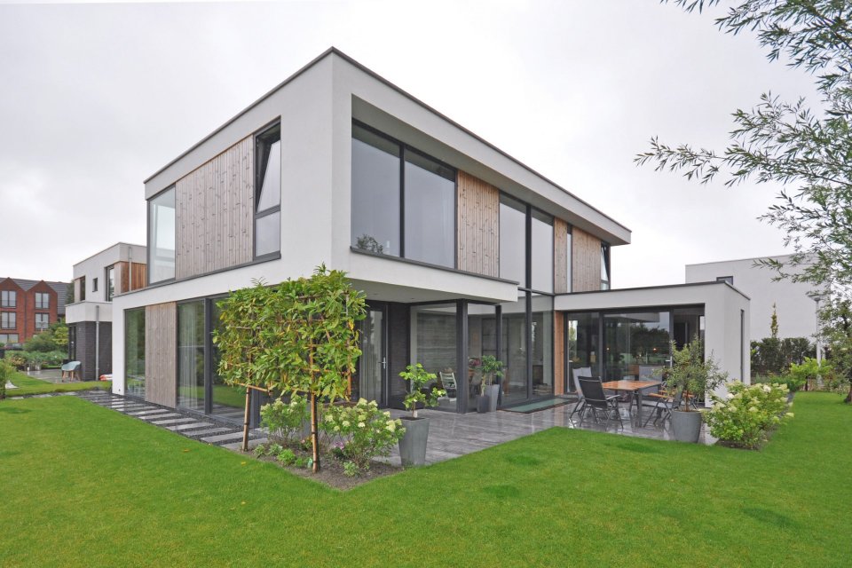 Moderne woning met witte gevels, houten accenten en grote glaspartijen aan de tuinzijde &ndash; ontwerp door architect Bongers Architecten