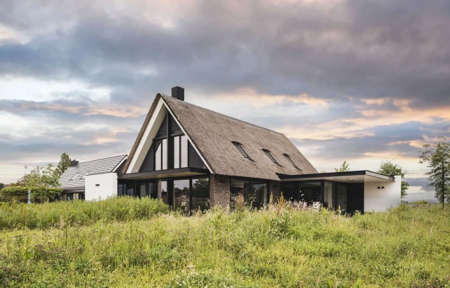 Hedendaagse woning, met rieten kap, gemetselde muren, grote raampartijen, aluminium lamellen, gestucte afwerking, vergunningsvrije aanbouw architectuur van Bongers architecten in Oud Alblas en aannemer Buitenhuis Villabouw in Alblasserdam