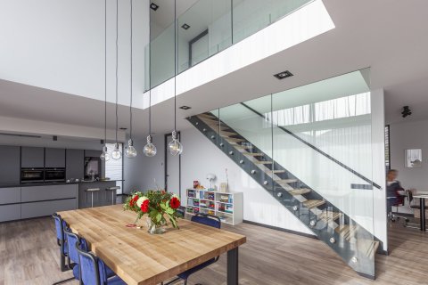 Lichte woonruimte met vide, glazen trap en maatwerk keuken in modern minimalistisch design &ndash; Bongers Architecten