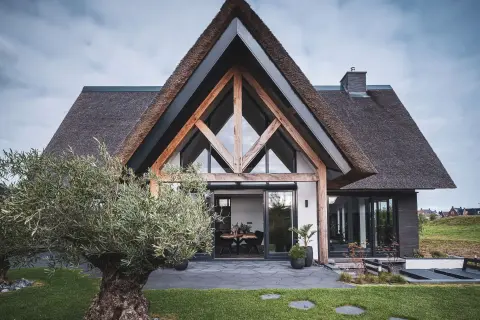 Rietgedekte moderne villa met hoge glaspartij, eiken spanten en zicht op het landschap &ndash; ontworpen door Bongers Architecten