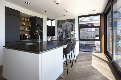 Lichte moderne keuken met zwart-wit kleurcontrast, maatwerk kasten en grote glaspuien &ndash; licht en zicht in architectuur