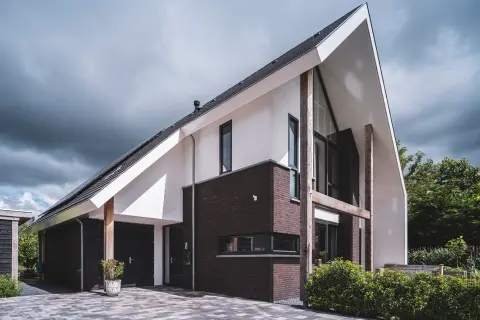 Villa met witte en donkere gevel, expressieve kapvorm en houten kolomaccenten &ndash; modern woningontwerp door Bongers Architecten