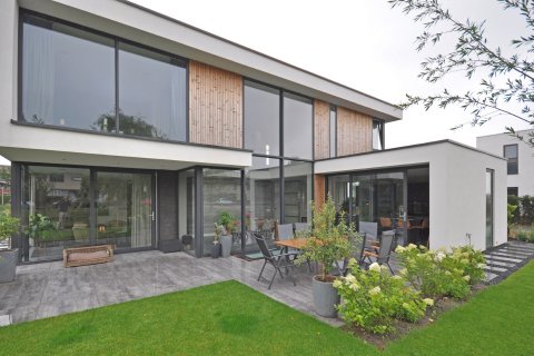 Moderne villa met witte gevels, houten accenten en grote glaspartijen aan de tuinzijde &ndash; maatwerk ontwerp door Bongers Architecten