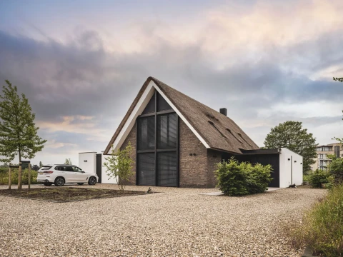 Hedendaagse woning, met rieten kap, gemetselde muren, grote raampartijen, aluminium lamellen, architectuur van Bongers architecten in Oud Alblas en aannemer Buitenhuis Villabouw in Alblasserdam