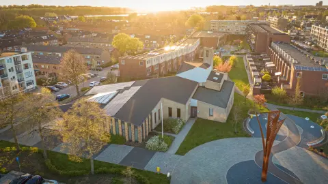 Moderne Ichtuskerk in Alblasserdam met houten gevel, asymmetrisch dak en groene inpassing in woonwijk.
