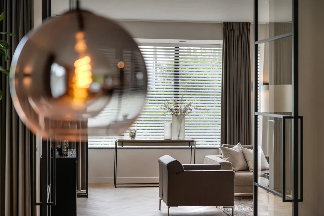 Zithoek met grote raampartij, stalen deuren en sfeervolle verlichting &ndash; moderne woning door architect Alblasserwaard.