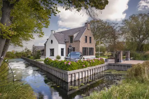Landelijke villa aan het water met bakstenen gevel, wit stucwerk en rieten kap &ndash; klassiek en karaktervol ontwerp door Bongers Architecten