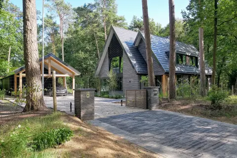 Moderne villa in bosrijke omgeving met donkere houten gevel en zadeldak &ndash; duurzaam ontworpen door Bongers Architecten.