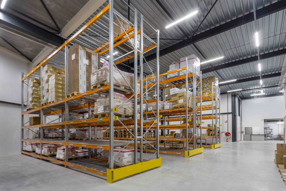 Ruim en functioneel magazijn met hoge stellingen en industri&euml;le afwerking &ndash; onderdeel van modern bedrijfspand ontworpen door architect Oud-Alblas.