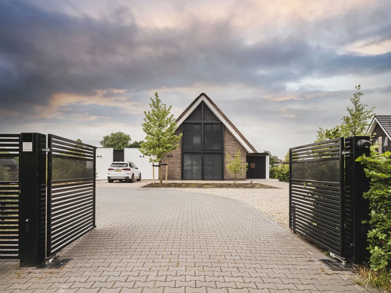 Hedendaagse woning, met rieten kap, gemetselde muren, grote raampartijen, aluminium lamellen, architectuur van Bongers architecten in Oud Alblas en aannemer Buitenhuis Villabouw in Alblasserdam, aluminium toegangspoort en hekwerk