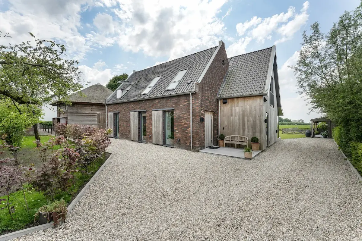 Landelijke woning met bakstenen gevel, houten accenten en zadeldak &ndash; eigentijds ontwerp in het buitengebied door Bongers Architecten.