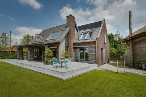 Gemoderniseerde woning met houten gevelaccenten, dakkapellen en royale schuifpui naar het terras &ndash; landelijke stijl met eigentijdse details.