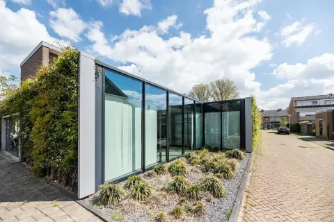 Herbestemd gebouw met strakke glasgevel, moderne aanbouw en duurzame invulling &ndash; licht en zicht in architectuur.
