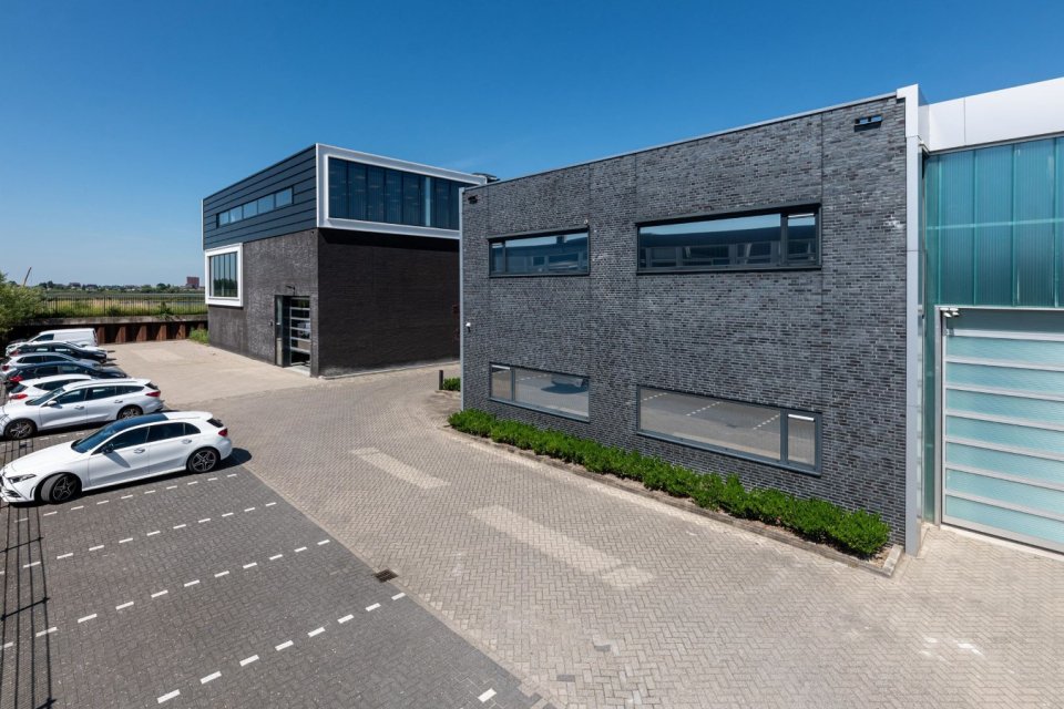 Strak ontworpen bedrijfspand met donkere baksteengevel, bandramen en glasstroken &ndash; eigentijds bedrijfspand ontwerpen.